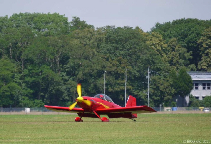 Zweisitzer Sportflugzeug / a red plane with a yellow propeller blade